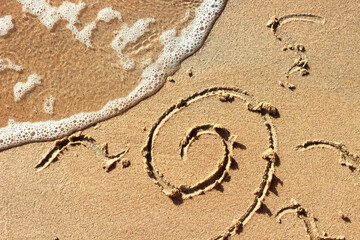 Painted sun on the sand by the sea. Beach.Sea sandy shore.