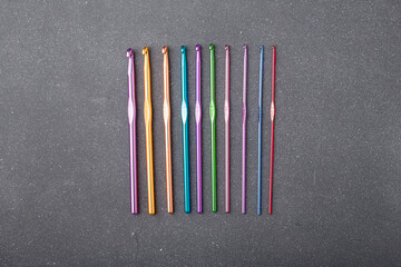 Metal crochet hooks set, crocheting tools kit of different gauge, thickness on grey background. Top view, copy space