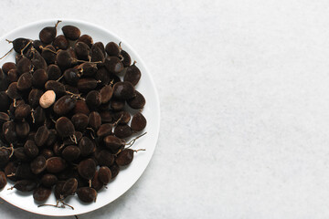 Overhead view of velvet tamarind on a white plate, top view of velvet tamarind bunch on white background