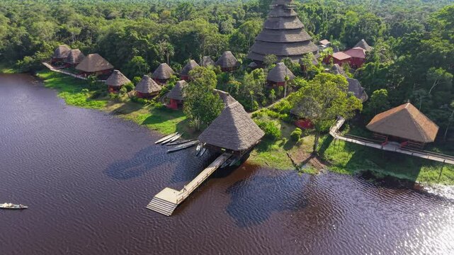 Lush greenery surrounds a tranquil eco lodge nestled beside a river in the heart of the Amazon rainforest, offering a unique blend of nature and comfort