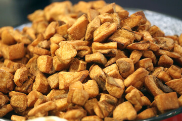 Heap of domestic salty fried pork greaves. Fatty junk food. Pork greaves for sale on farmers market stall