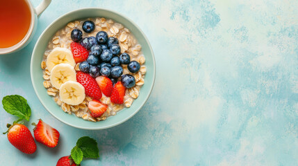 A healthy breakfast with a bowl of oatmeal topped with fresh fruits like bananas, strawberries, and blueberries, placed next to a cup of herbal tea