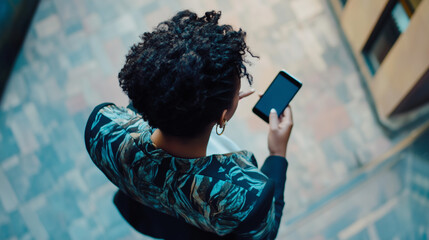 A black working woman is standing with her back playing on her cell phone.