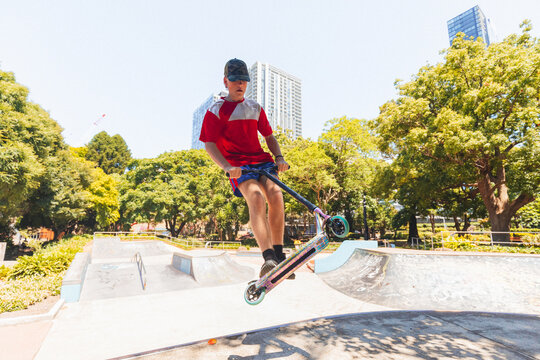 Teenage boy riding scooter on ramps at skate park
