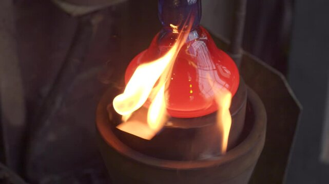 Manual glass production. Glassblower shaping molten glass with a torch in a workshop
