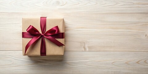 Fototapeta premium A Beautifully Wrapped Present with a Deep Red Ribbon on a Light Wooden Surface
