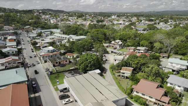 Drone flies west from Santa Elena over the Macal River into downtown San Ignacio, Belize on sunny afternoon