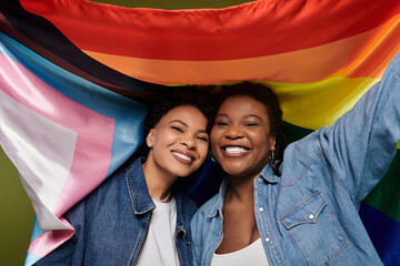 Loving lesbian couple celebrates pride in stylish denim with vibrant rainbow flag