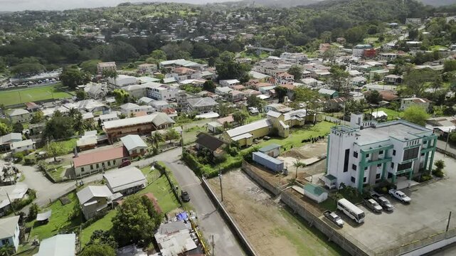 Drone orbits to the left from Town Hall down to the soccer fields and the Saturday Market next to the Macal River in San Ignacio, Belize on sunny day