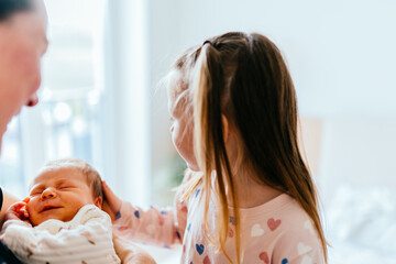 Big sister gently touching newborn baby s head