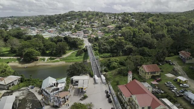 Drone flies east over metal suspension Hawkesworth Bridge from San Ignacio to Santa Elena, crossing the Macal River on sunny day
