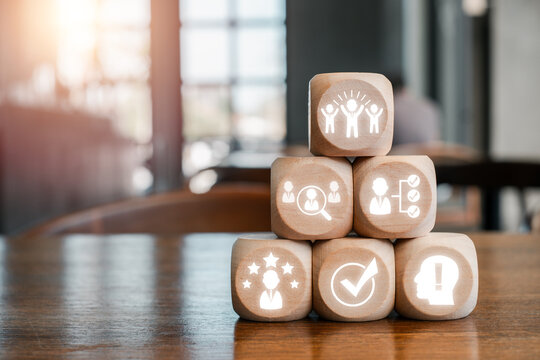 Wooden blocks with business icons representing assessment center concepts in a modern office environment.