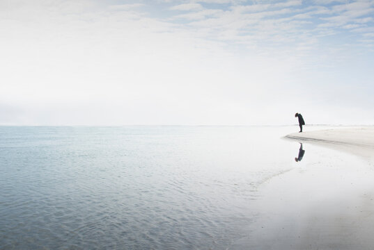 Silhouette of woman staring at edge of water