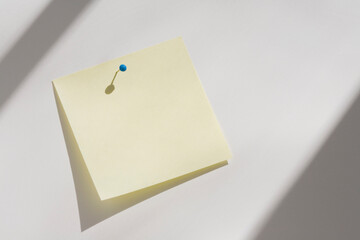 Blank yellow adhesive note pinned to white board