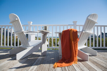 Two adirondack chairs on deck of seaside cottage