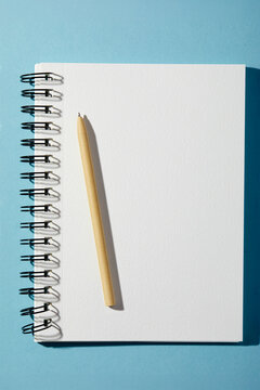 Spiral notebook and pen on blue background