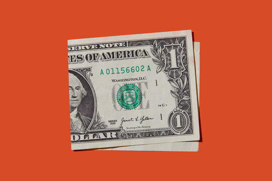 Folded one dollar bill on orange background