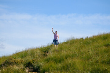 Woman in sunglasses standing on grassy field and waving
