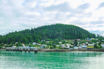 Pier and town with forested hill in background seen across water