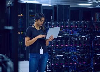 Female technician using laptop in server room