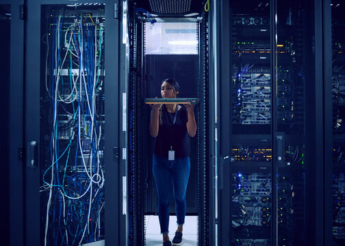 Female technician holding hard drive in server room