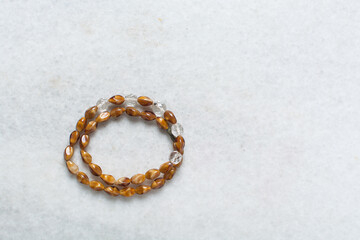 Overhead view of brown vintage necklace on marble jewelry holder, top view of vintage brown beaded necklace on a white background