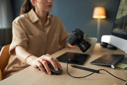 Person working at desk with computer and camera in comfortable, well-lit workspace focusing on task with attention to detail