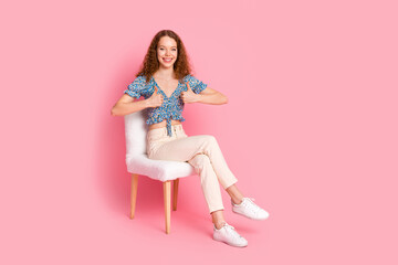 Cheerful woman giving thumbs up sitting on a stylish chair