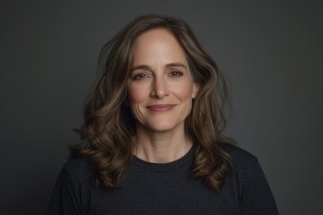 Fototapeta premium A picture of a woman with long wavy hair smiling against a grey background