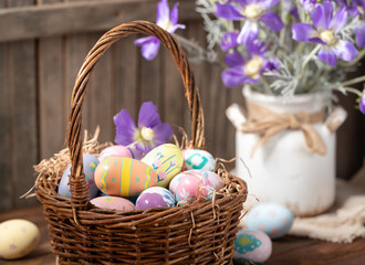 Decorated Easter eggs in a basket and vase with purple daisies