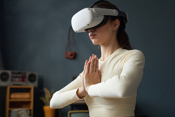 Woman engaged in yoga session indoors while wearing virtual reality headset, enhancing concentration and mindfulness in calm environment
