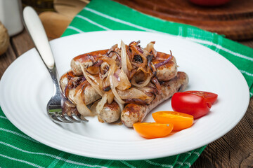 Fried Fried white sausages with onion on the plate.white sausages in a cast iron skillet.