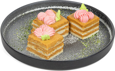 Three delicious cakes with pink frosting served on a black plate