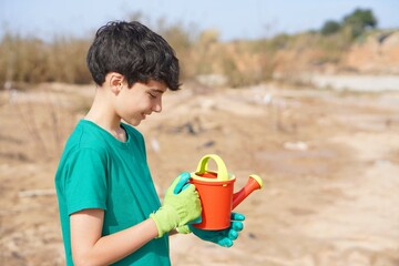 education. child with gloves and watering can during a planting and environmental care activity.