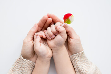 Childs hand holding lollipop with adult supportive hands