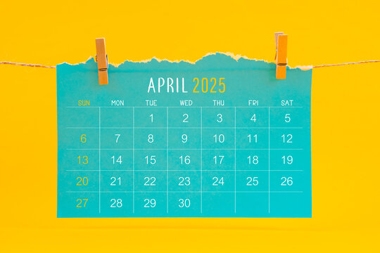 April 2025 calendar tearing hanged with brown rope on yellow background.