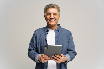 Mature man with tablet smiling against plain background in a well-lit studio setting