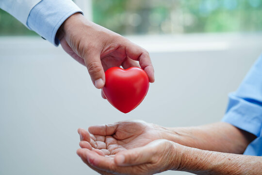 Asian elder senior woman patient holding red heart in hospital.