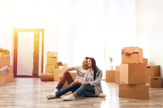 Happy couple in sunlit room with cardboard boxes on moving day