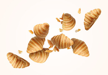 Delicious croissants and crumbs in air on white background. Puff pastry