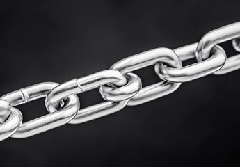 Obraz premium Close up view of a metallic chain against a dark background. The chain shows signs of wear, with some links appearing scratched or slightly damaged