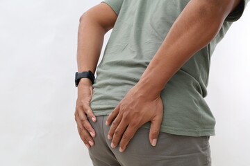 Close up photo of a man standing holding his buttocks