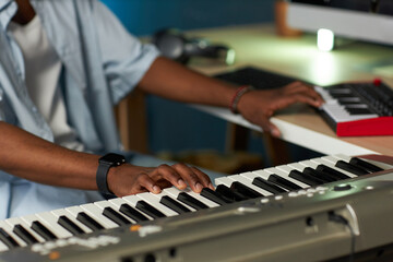 Obraz premium Close-up view of hands playing electronic keyboard in modern music studio with equipment in background creating harmonious melody in relaxing environment