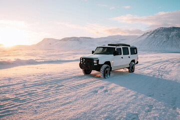 Off-Road 4x4 Vehicle Driving Through Snowy Landscape at Sunrise