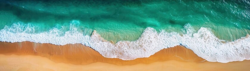 Aerial view of a sandy beach meeting turquoise ocean waves.