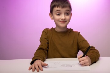 Naklejka premium Child in brown sweater drawing on paper at a desk, purple background. Ideal for themes of creativity, childhood education, play, and artistic expression.