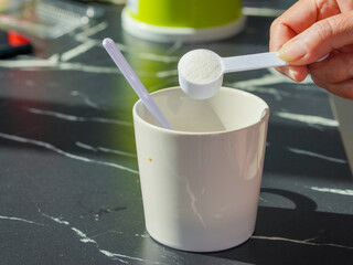 Lifestyle Health care. Hands of a person scooping collagen powder from a jar with a scoop. Collagen, which contains vitamins, helps nourish, anti age and restore the body's deterioration.