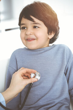 Doctor-woman examining a child patient by stethoscope in sunny clinik. Medicine concept