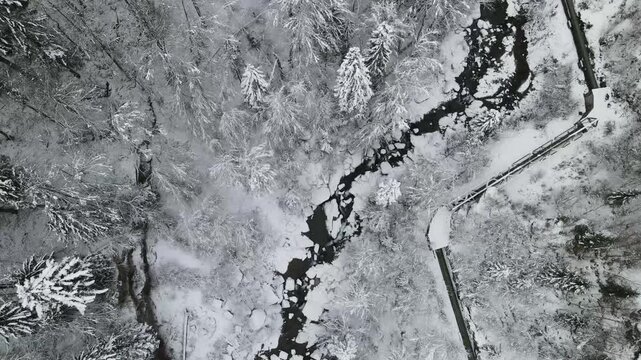 Stunning aerial view of Gunzesrieder Tobel and Gunzesrieder Ach in winter, featuring a frozen reservoir, thick layers of snow, and untouched nature in a remote mountain valley.