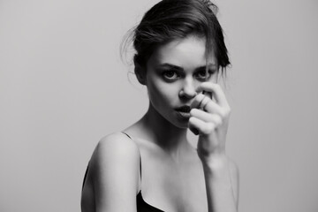 Thoughtful young woman in a minimalist black and white portrait, gently touching her face with an...